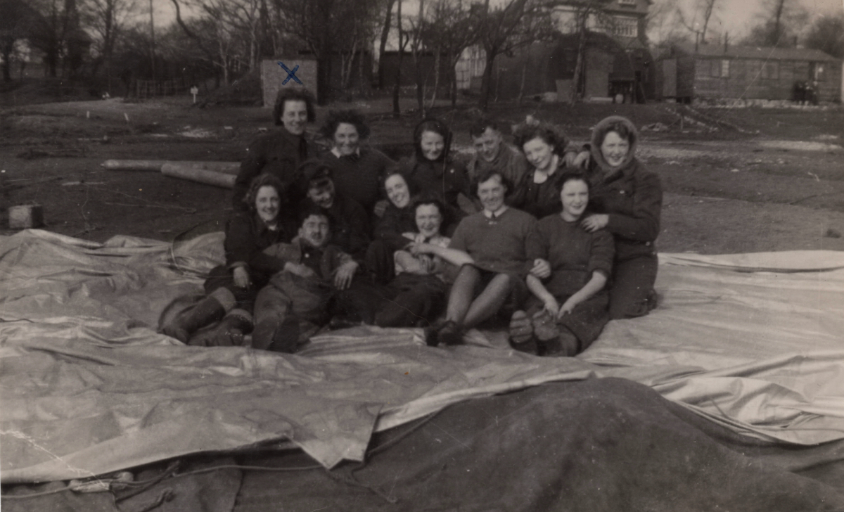 Balloon operators sitting on a deflated barrage balloon in ‘Manchester 1942’ as she later wrote on the back of the photo. Margrete Jepsen is first from left in the back row.