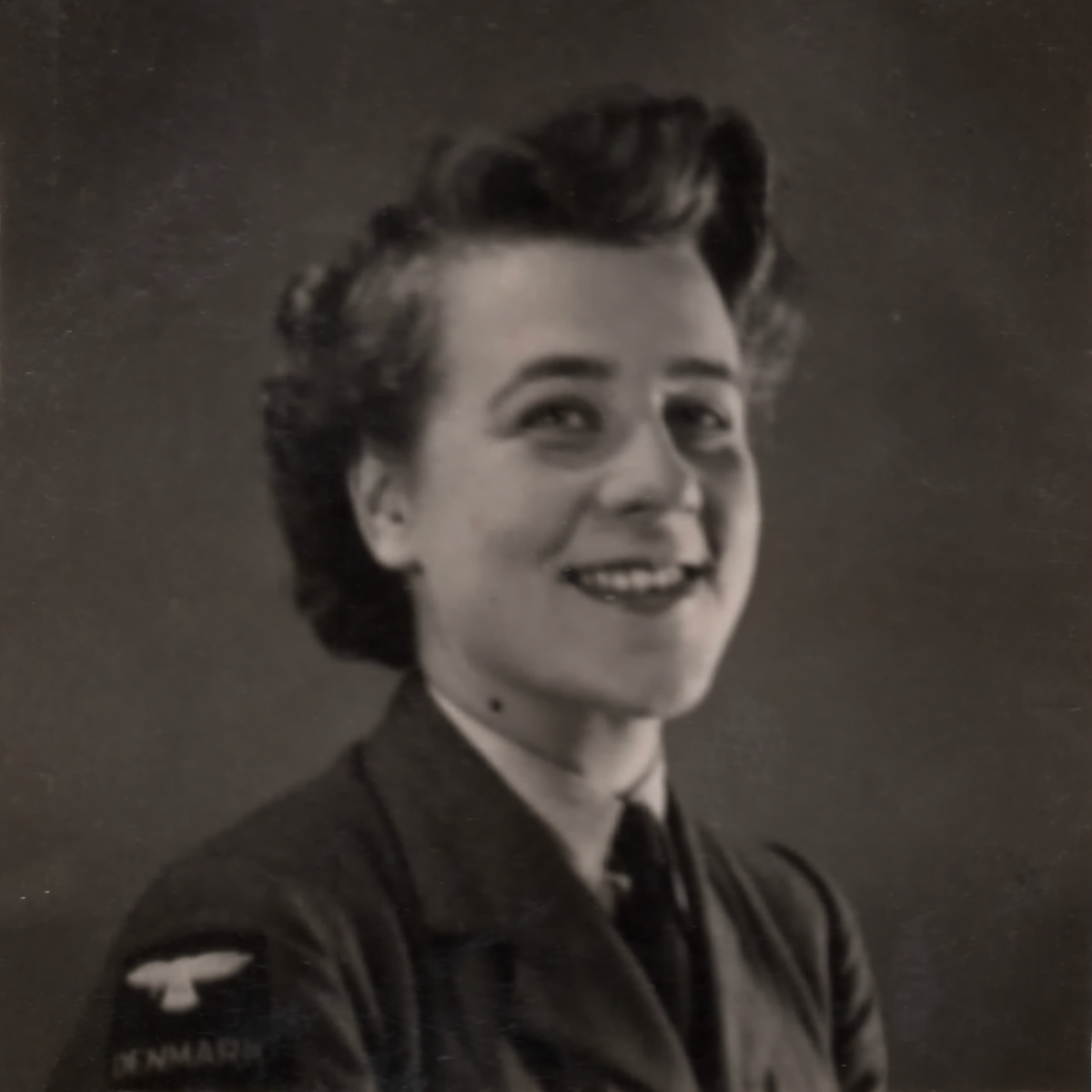 Corporal Marie Jepsen (2047937) in her uniform, wearing the DENMARK shoulder flash on her shoulder. This suggests that the photo was taken in 1944 at the earliest.